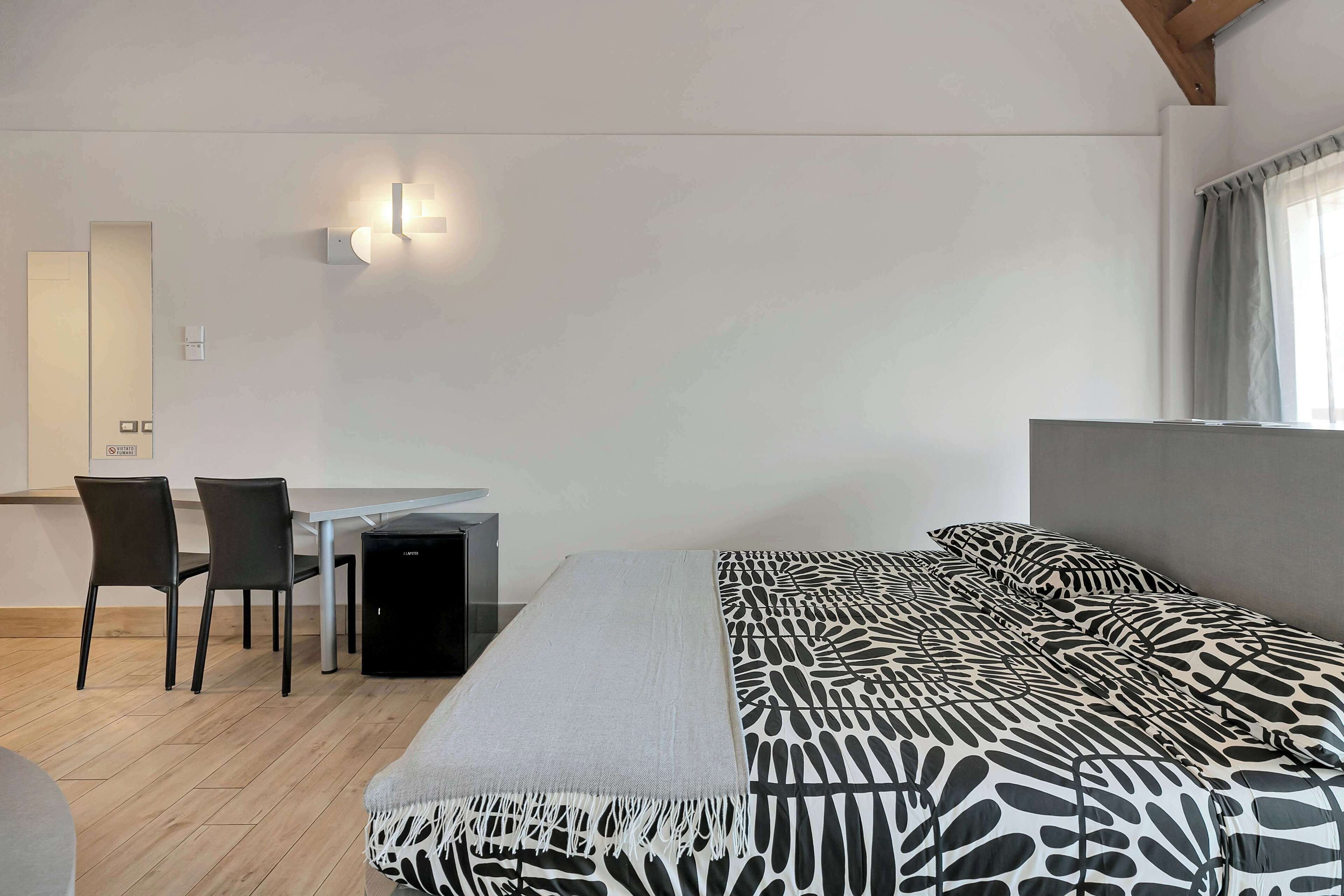 Une chambre à coucher avec un lit, un bureau et deux chaises.