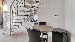 A modern interior with a spiral staircase, a round dining table, and black chairs. - Suite A Tema (Milan)