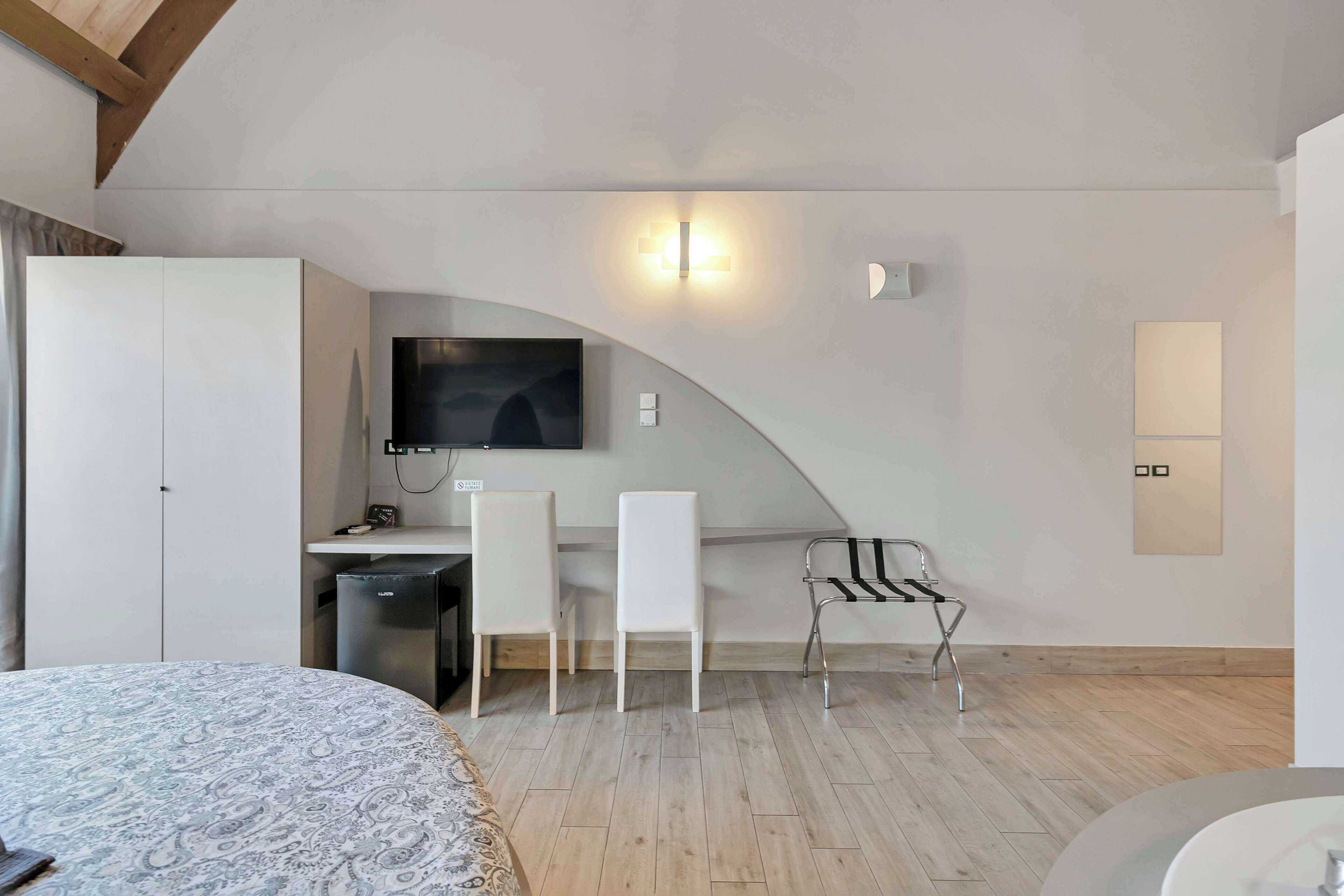 Une chambre à coucher moderne comprenant un lit, un bureau avec une chaise, une télévision et une armoire.