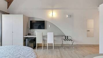 Une chambre à coucher moderne comprenant un lit, un bureau avec une chaise, une télévision et une armoire.