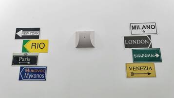 Una pared con señales direccionales que indican diferentes ciudades como Nueva York, Río, París, Milán, Londres, Shanghái y Venezuela.