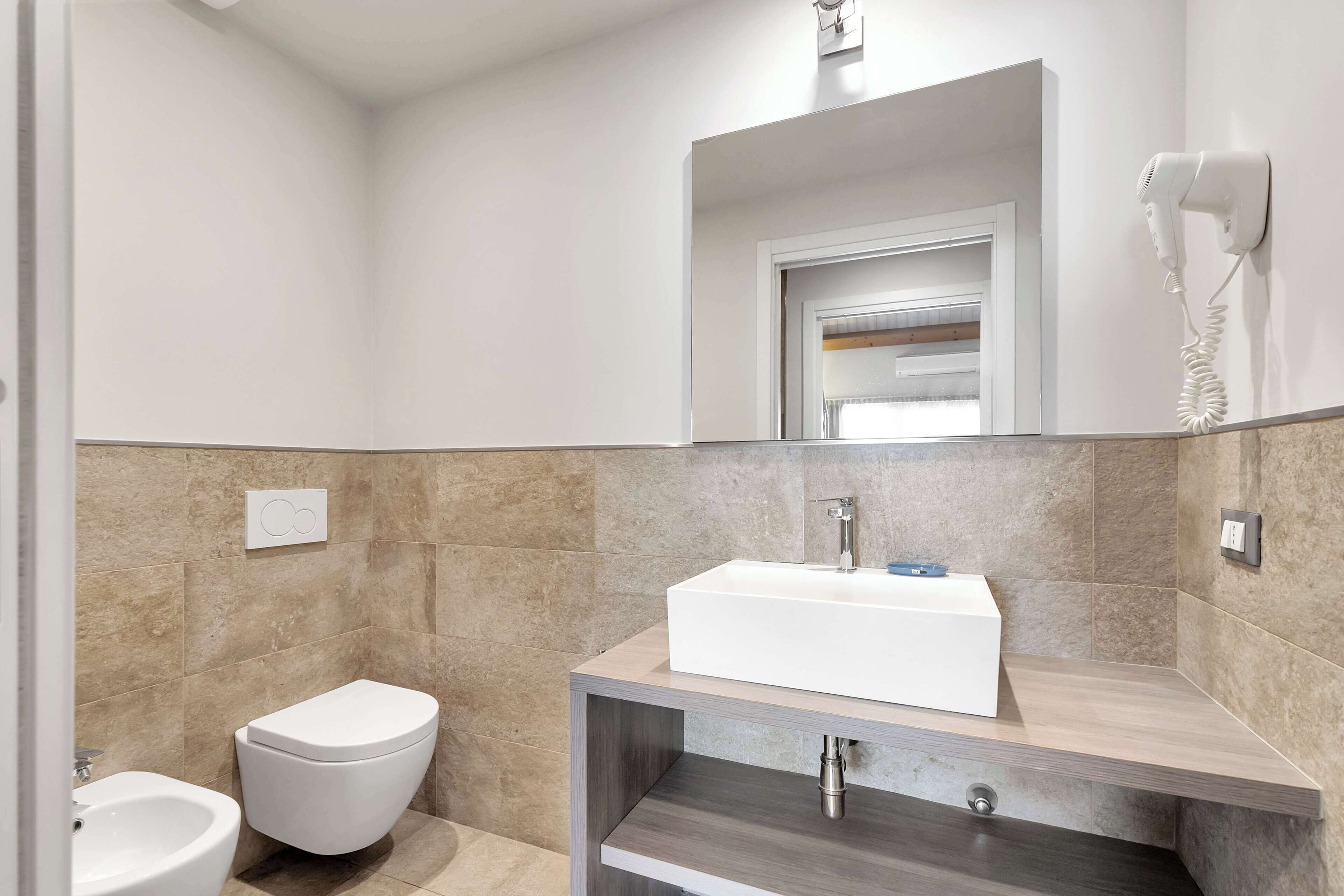 A modern bathroom with a white sink, a toilet, and a bidet.