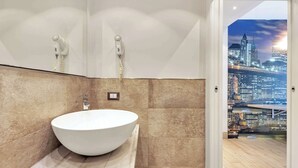 A modern bathroom with a large white sink, a mirror, and a cityscape view through an open door. - Suite A Tema (Milan)