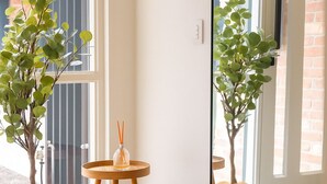 Ein Zimmer mit einem großen Spiegel, der eine Pflanze und einen kleinen Tisch mit einer Kerze reflektiert.