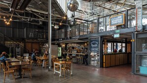 Ein geräumiges Café mit mehreren Tischen und Stühlen, einer Balkonbar und einem sichtbaren Ausgangsschild.
