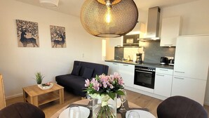 A modern kitchen with white cabinets, a black oven, and a dining area with a round table set for four. - Winterberg Apartment Near ski Area (Winterberg)