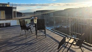 A rooftop terrace with a table and chairs, overlooking a cityscape. - Winterberg Apartment Near ski Area (Winterberg)