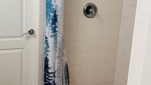 A bathroom with a shower, tiled walls, a door, and a curtain with a tree pattern. - Spacious 3-bedroom house in brilliant Austin  /The Domain & Q2 Stadium/ (Austin)
