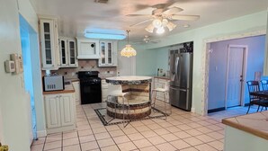 A kitchen with white cabinets, a black stove, a stainless steel refrigerator, a ceiling fan, and a tiled floor. - Spacious 3-bedroom house in brilliant Austin  /The Domain & Q2 Stadium/ (Austin)