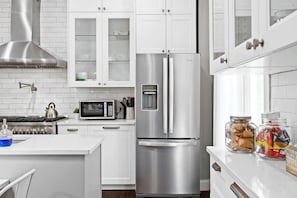 A modern kitchen with white cabinets, stainless steel appliances, and a built-in microwave.