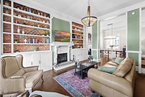 Ein Wohnzimmer mit Kamin, Bücherregalen, einem Couchtisch und einer Couch.