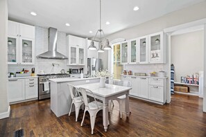 A modern kitchen with white cabinetry, a central island, and a stainless steel range hood.