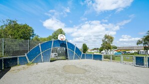 An outdoor basketball court with a blue fence, a basketball hoop, and a clear sky. - 6 Person Holiday Park Home in Faaborg (Faaborg)