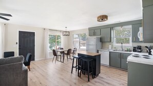 Una cocina moderna con comedor, suelo de madera y un amplio ventanal que aporta luz natural.