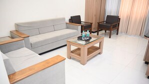 Een moderne woonkamer met een grijze bank, een houten salontafel en twee fauteuils.