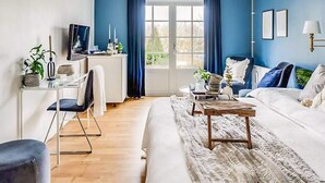 A modern living room with a blue accent wall, a white sofa, a wooden coffee table, and a desk with a chair. - 2 Person Holiday Park Home in Bastad (Bastad)