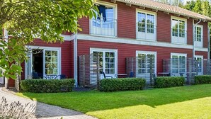A two-story building with a red exterior and white trim, featuring a front porch with a bench and a small table. - 2 Person Holiday Park Home in Bastad (Bastad)