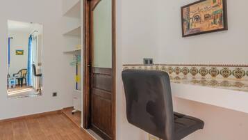 A room with a wooden door, a black office chair, a tiled backsplash, and a framed picture on the wall.