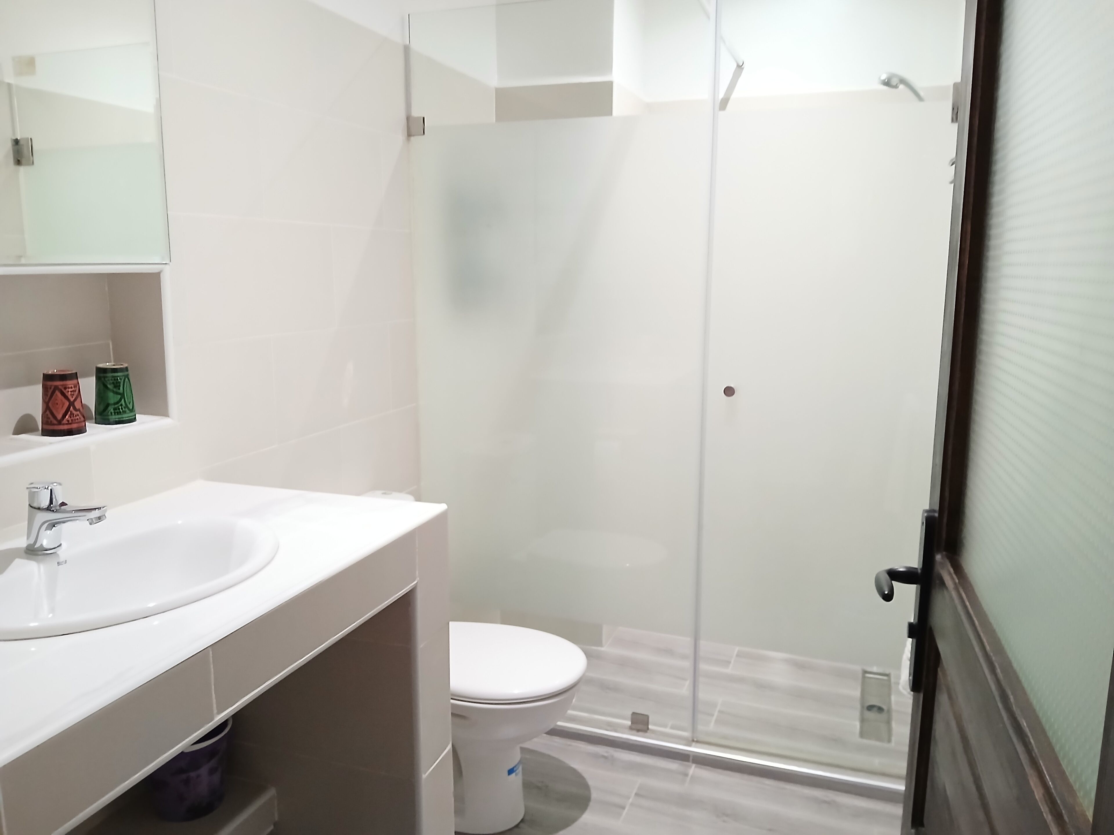 A modern bathroom with a glass shower enclosure, a white sink, and a toilet.