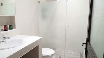A modern bathroom with a glass shower enclosure, a white sink, and a toilet.