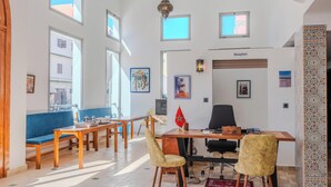 Une pièce spacieuse comprenant un comptoir d’accueil, un canapé bleu, une table à manger en bois et des chaises.