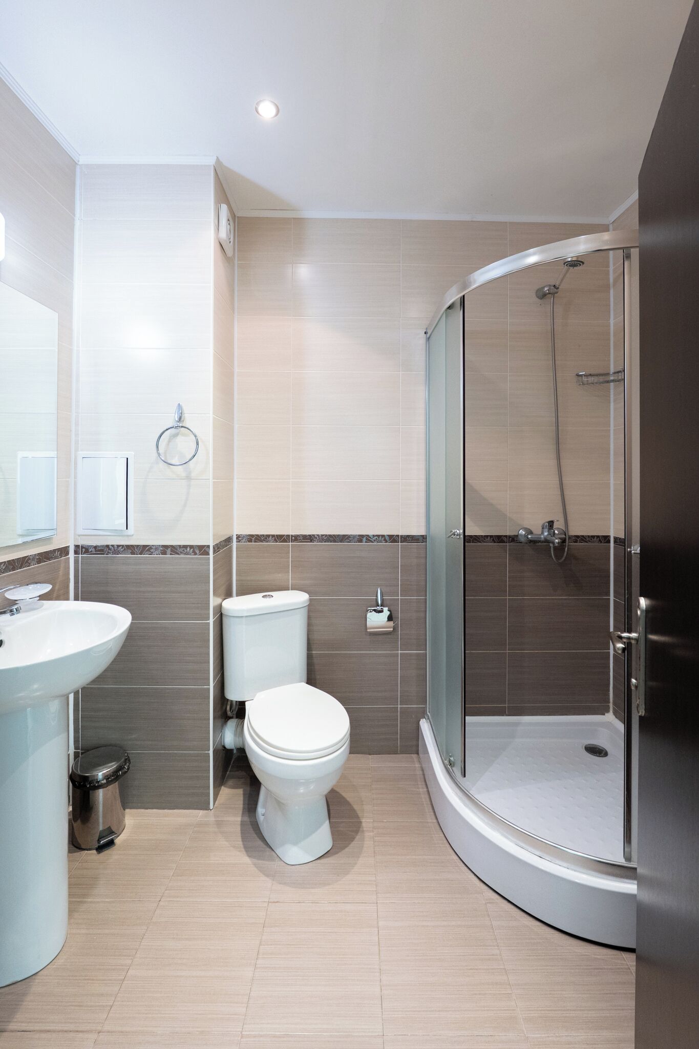 A modern bathroom with a curved shower enclosure, a toilet, and a sink.