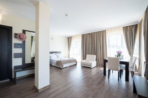 A hotel room with a bed, a chair, a desk, and a dining table.