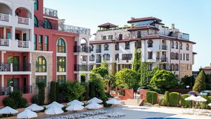 A hotel with a swimming pool, multiple balconies, and outdoor seating areas.