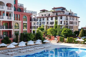 A hotel with a swimming pool, multiple balconies, and outdoor seating areas.