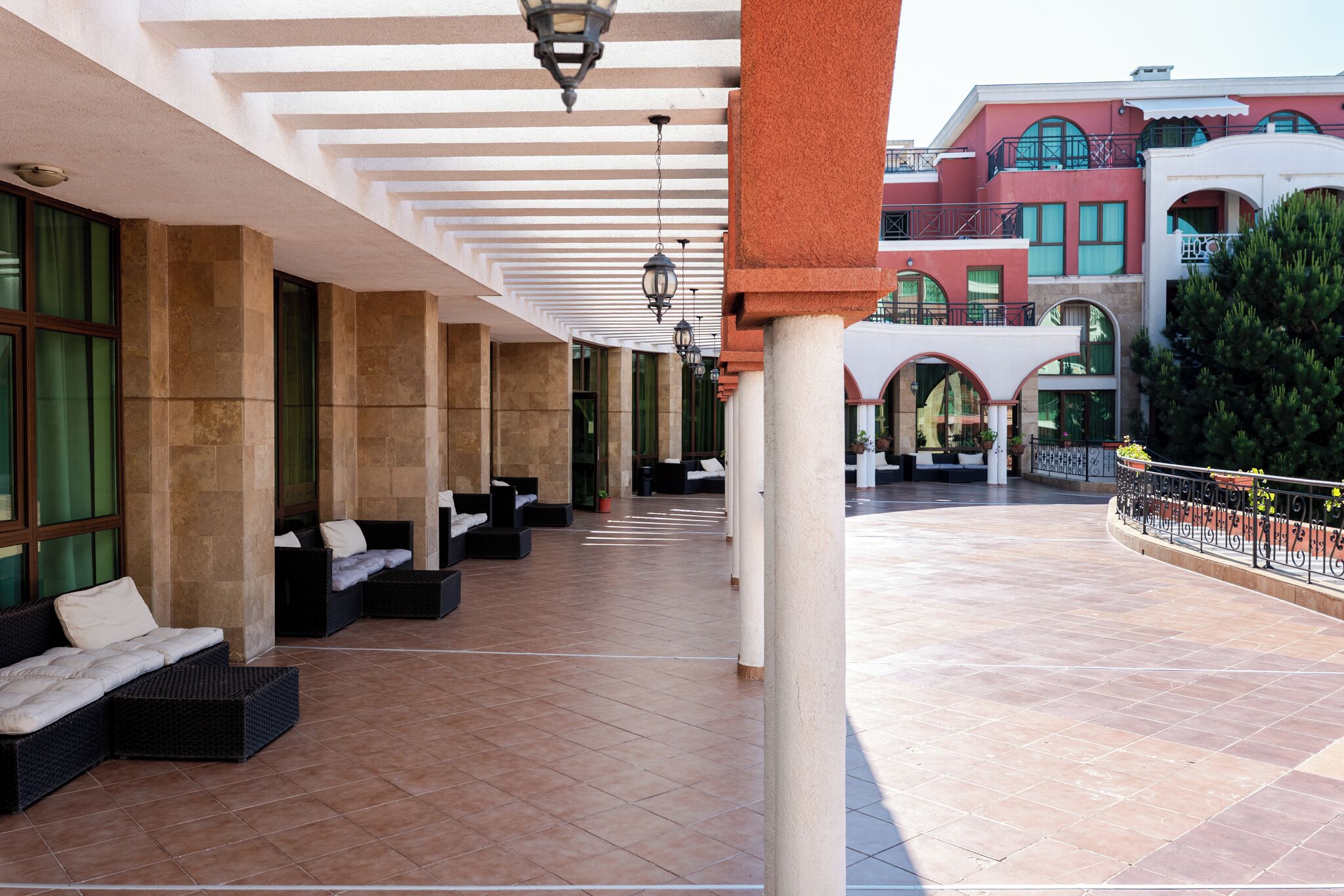 A covered outdoor seating area with wicker furniture and a tiled floor.