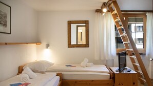 Ein Schlafzimmer mit zwei Holzbett, einem Holzschrank, einem Fernseher und einer Leiter.