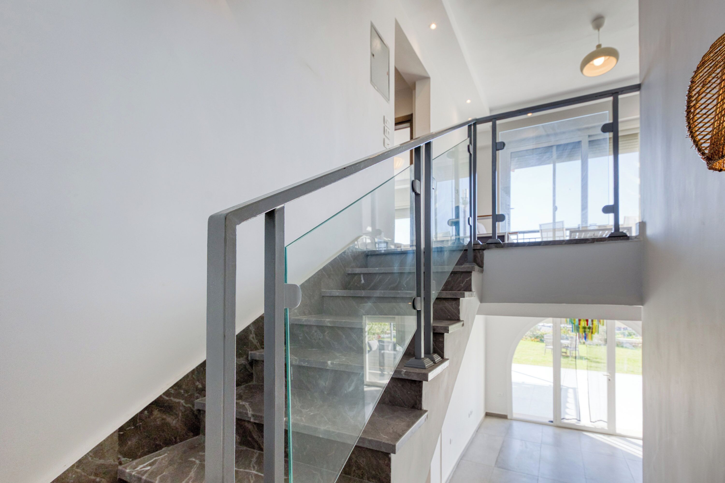 Un escalier moderne avec des rampes en verre menant à un deuxième étage.