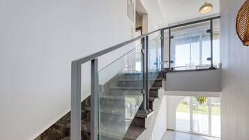 Un escalier moderne avec des rampes en verre menant à un deuxième étage.