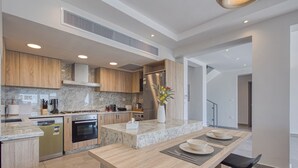 A modern kitchen with wooden cabinets, a built-in oven, and a marble countertop. - Prime Holidays Mountain View Ras ElHekma (El Dabaa)
