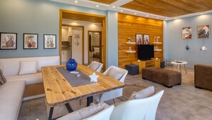 A modern living room with a wooden dining table, white sofas, and a TV. - Prime Holidays Mountain View Ras ElHekma (El Dabaa)