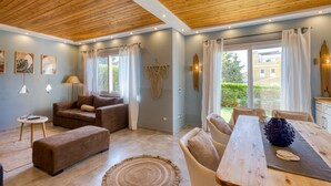 A modern living room with a wooden ceiling, a sofa set, a dining table, and a view of the outside. - Prime Holidays Mountain View Ras ElHekma (El Dabaa)
