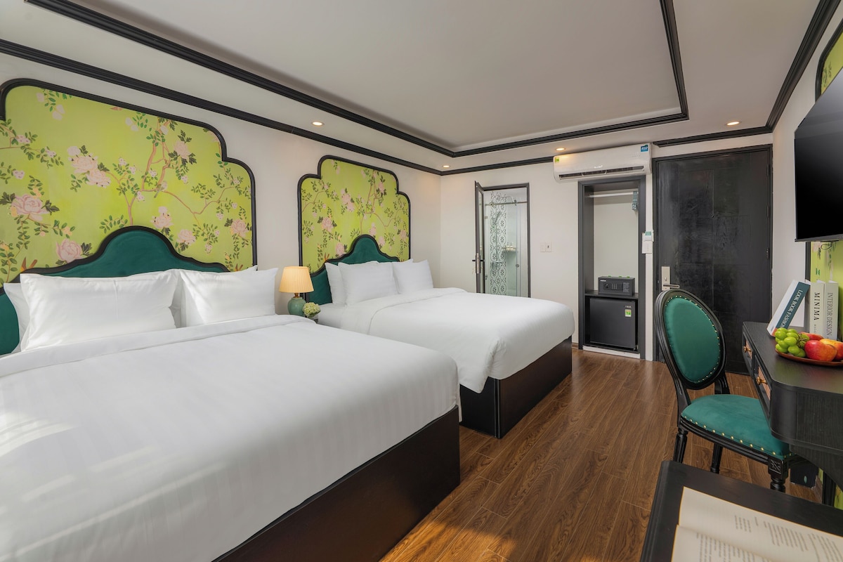 Une chambre d’hôtel avec deux lits, un bureau avec une chaise et une télévision.