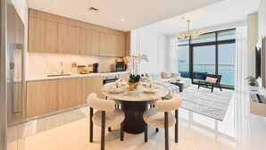 Una cocina moderna con armarios de madera, encimera de mármol y zona de comedor con una mesa redonda y sillas.