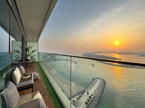 Un balcone con ringhiera in vetro che si affaccia su un'acqua e un tramonto.