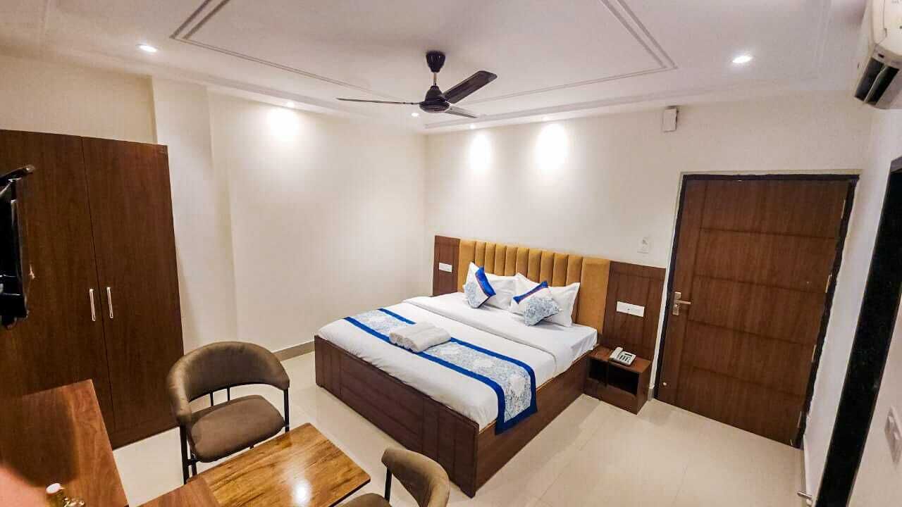 Ein Hotelzimmer mit Bett, Schreibtisch, Stuhl, Kleiderschrank und Deckenventilator.
