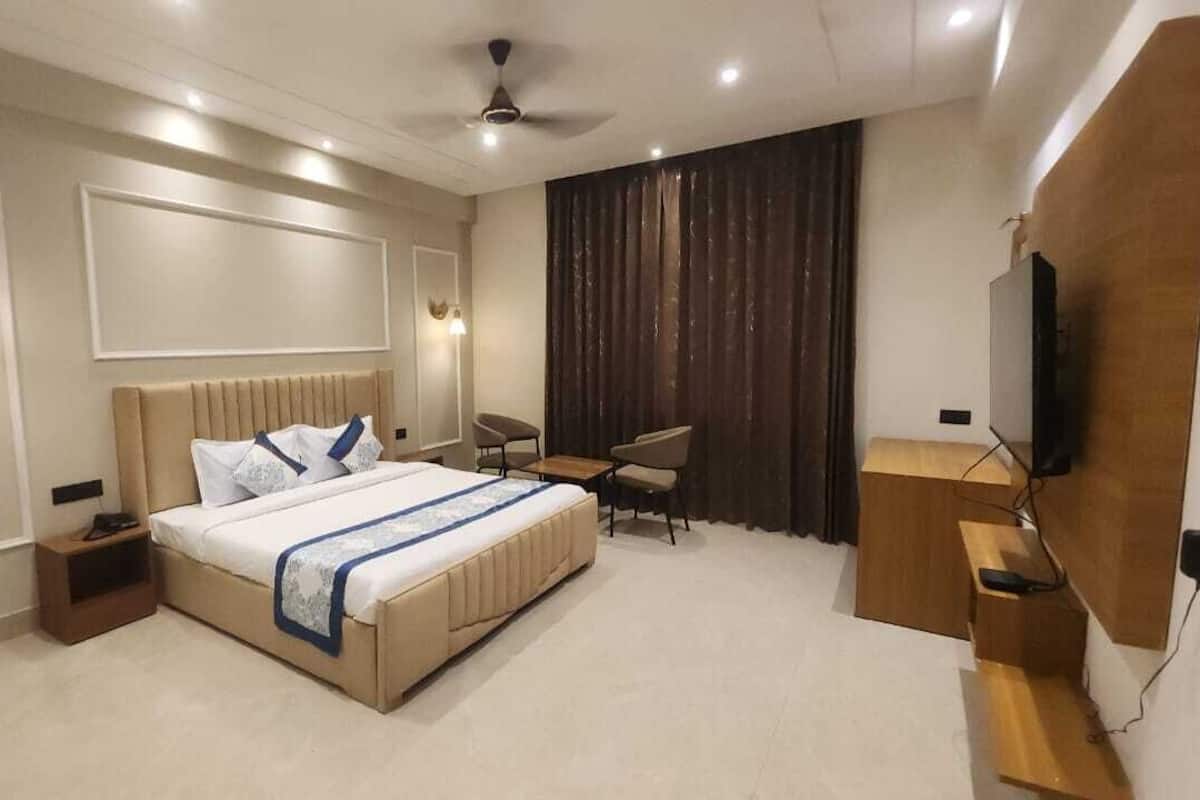 Un dormitorio moderno con una cama grande, mesitas de noche, un escritorio, una silla y un televisor.