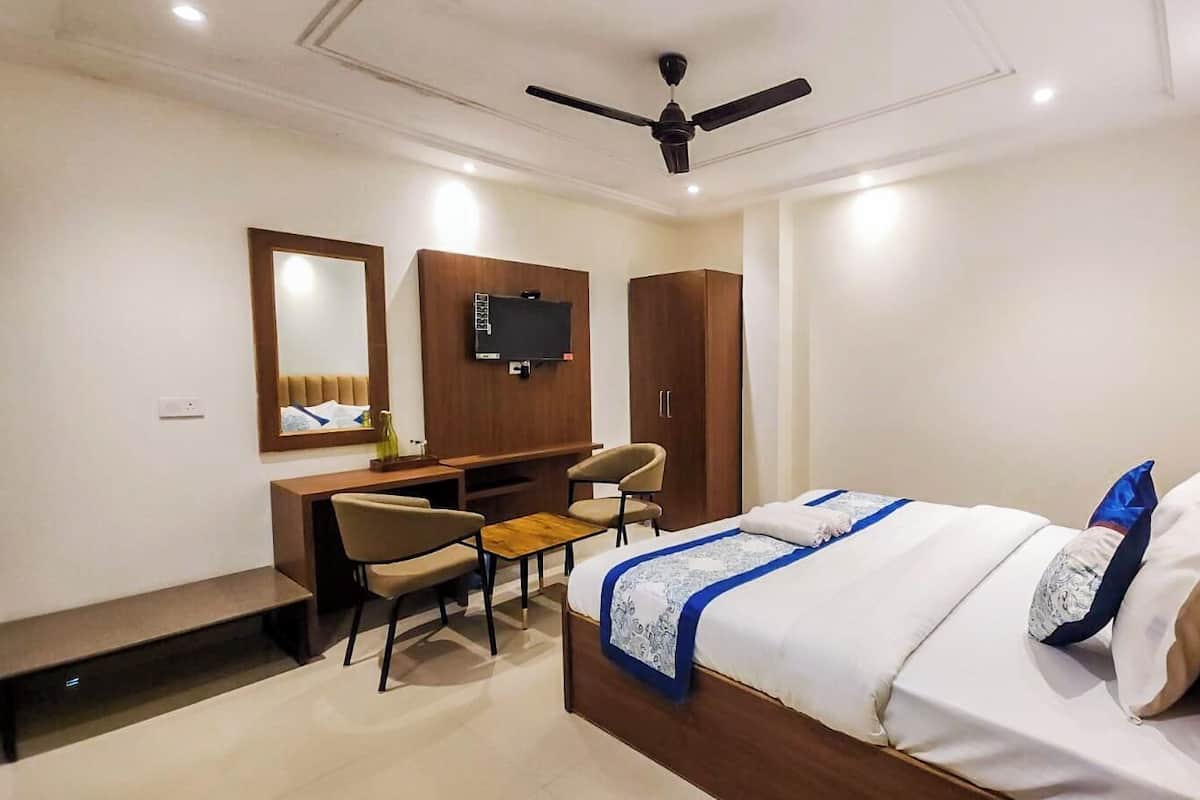Una habitación de hotel con cama, escritorio, silla, televisor y armario.