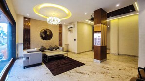 A modern lobby with a sofa, a chandelier, and a circular wall design. - THE MAJESTIC GRAND (Chandigarh)