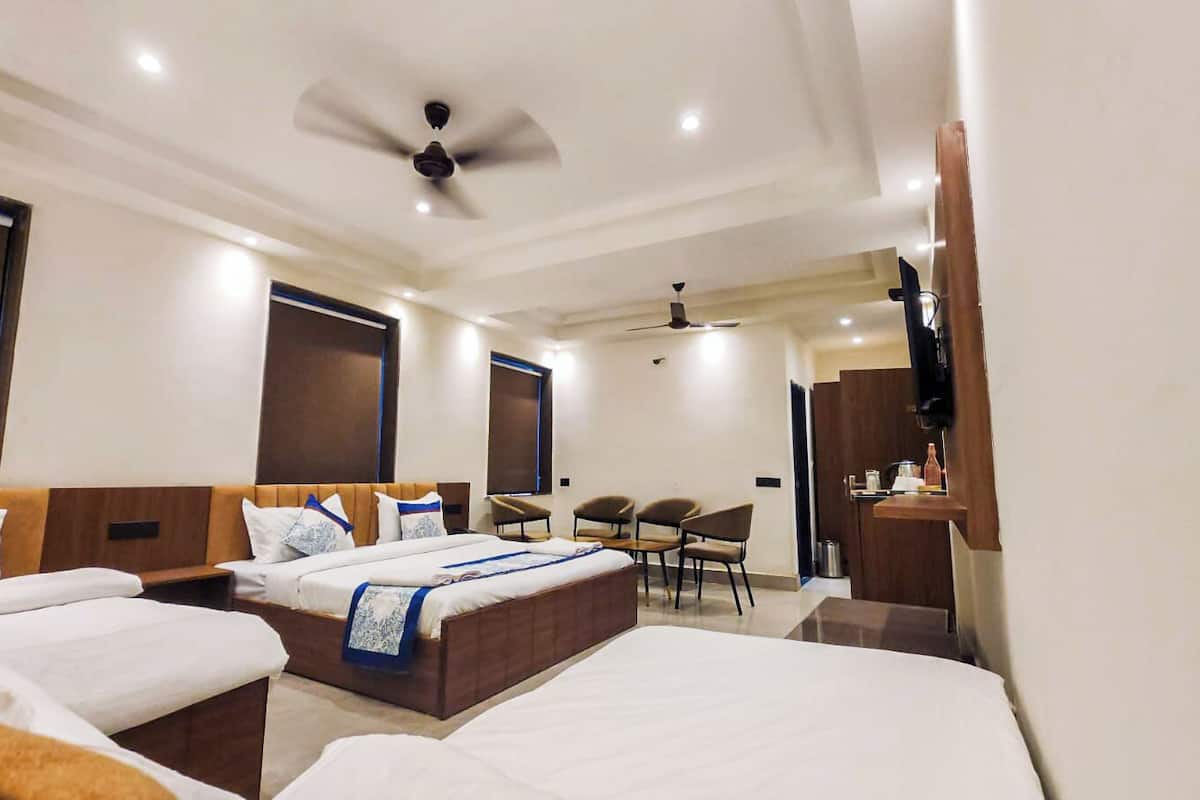 Habitación de hotel con dos camas, un escritorio, una silla, un televisor y un ventilador de techo.