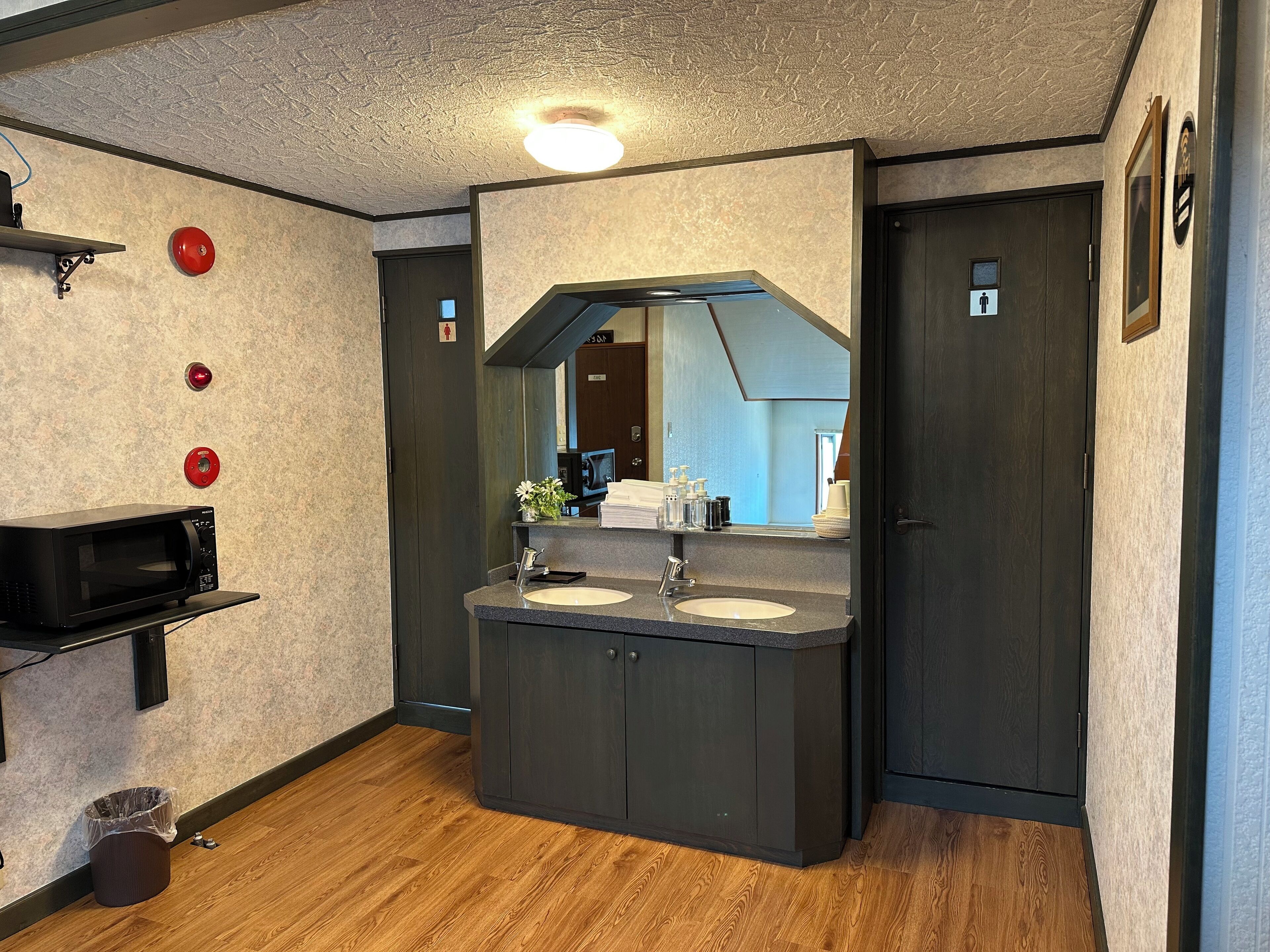 A modern bathroom with a double sink vanity, a mirror, and a trash bin.