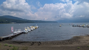 Un muelle junto al lago con varios barcos y cielo despejado.