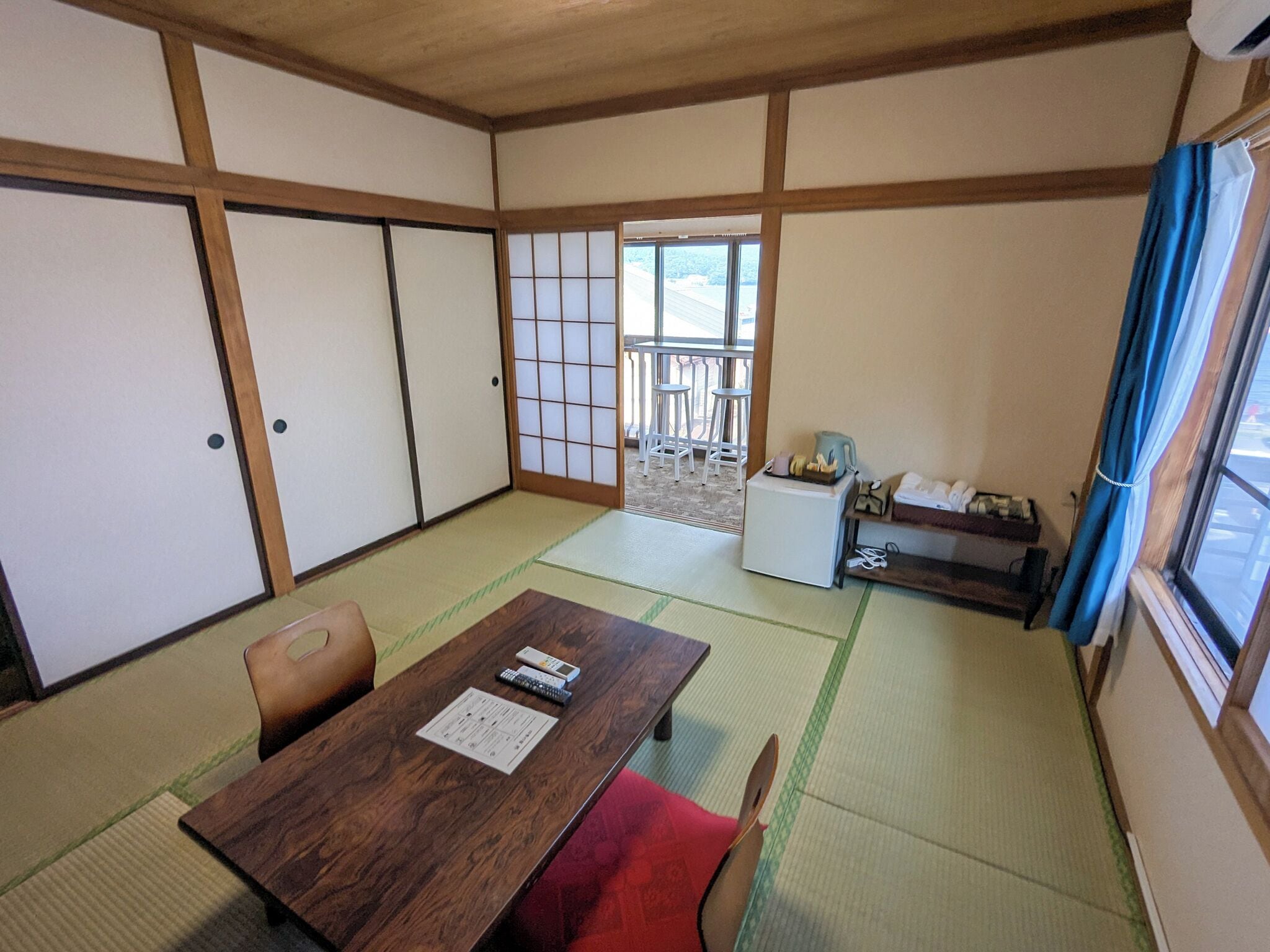 Una habitación japonesa tradicional con suelo de tatami, una mesa de madera baja y puertas correderas.
