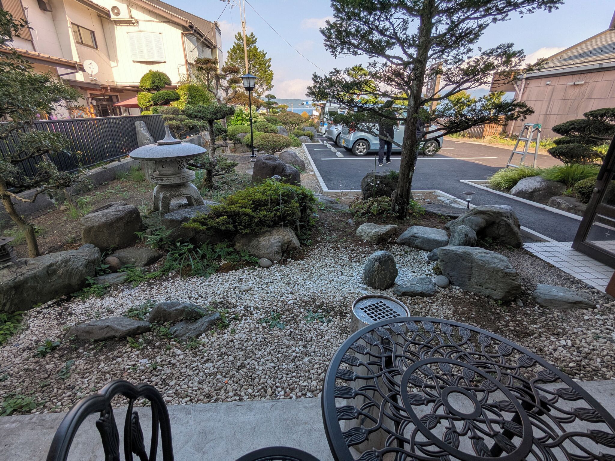 Un jardín con rocas, un farol de piedra y una mesa de metal.