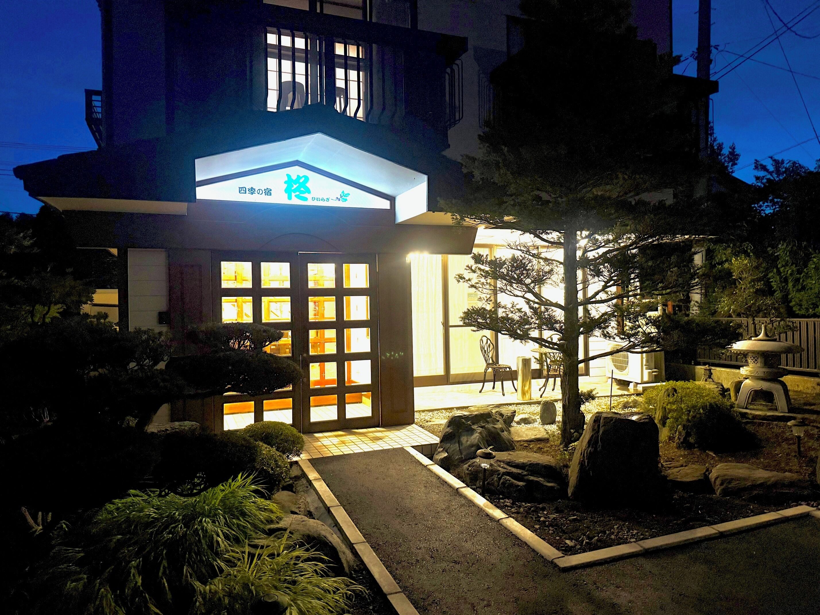 A traditional Japanese-style building with a wooden gate and a well-maintained garden.