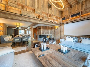 Un salón amplio con chimenea, una pantalla grande y un conjunto de asientos acogedor.